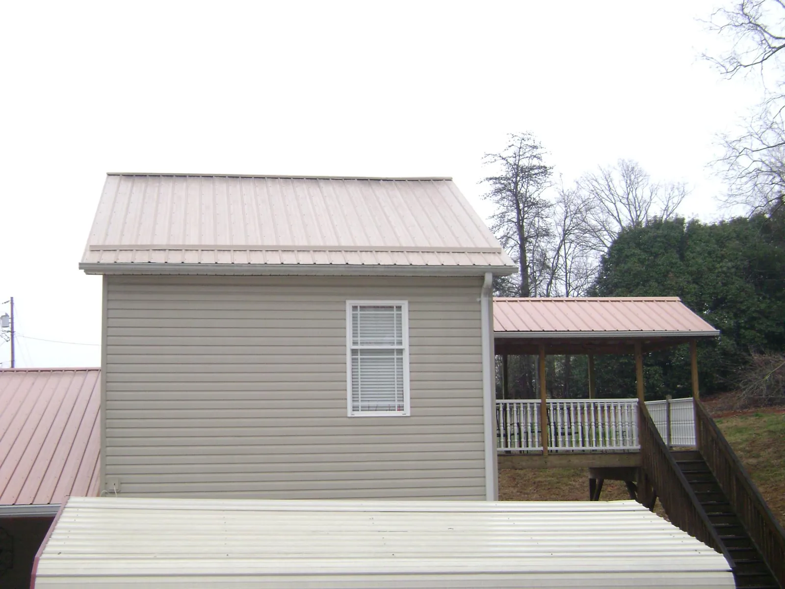 Tan metal roofs on a two story addition and attached porch, from a Roof Replacement job in Kahului