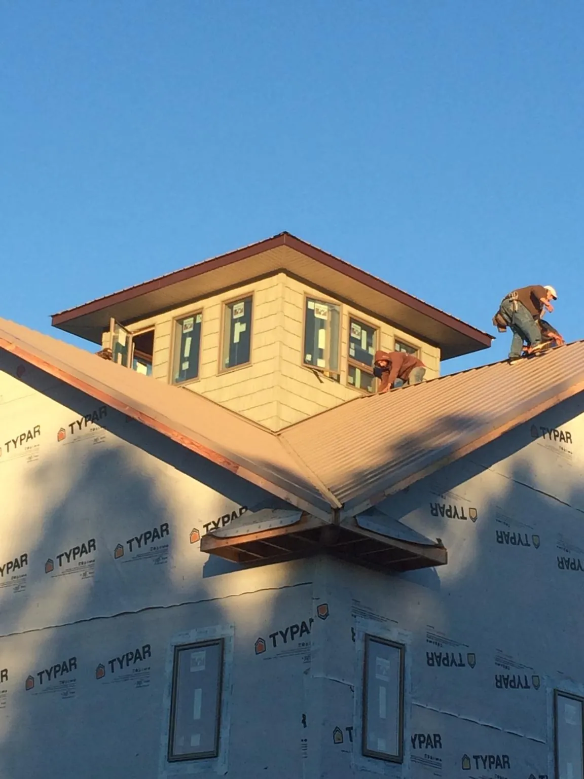 Roofers working around a rooftop cupola on a new metal roof at sunset — Roof Waterproofing in Kahului by Roofing Brothers